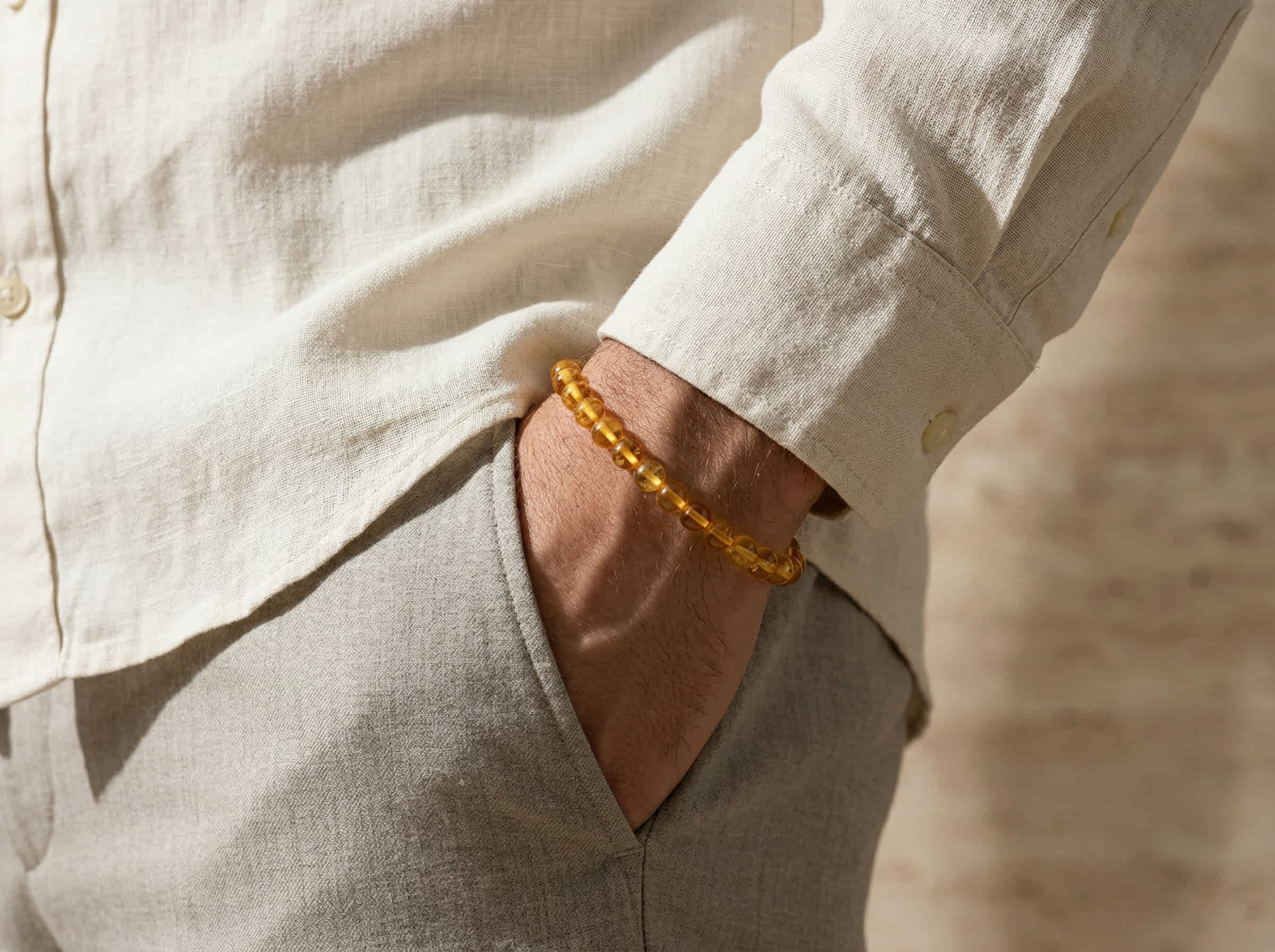 Polsfoto man met wit over shirt en armband hangemaakt van ronde barnsteen stenen 8mm