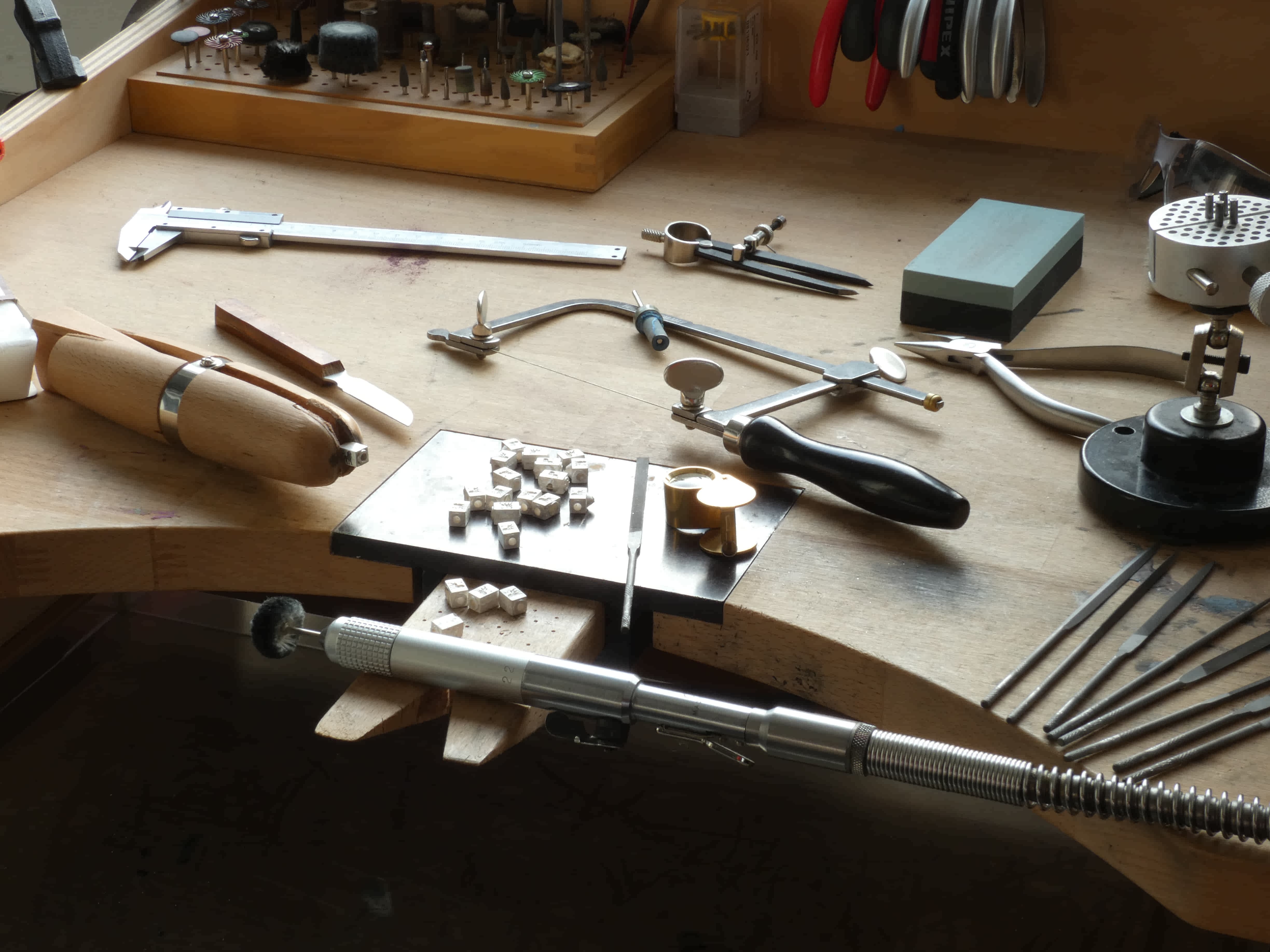 goudsmit bureau met een loep en diverse vijlen, tangen, hangmotor, zaag en zilveren voloria leeuw logo kubus