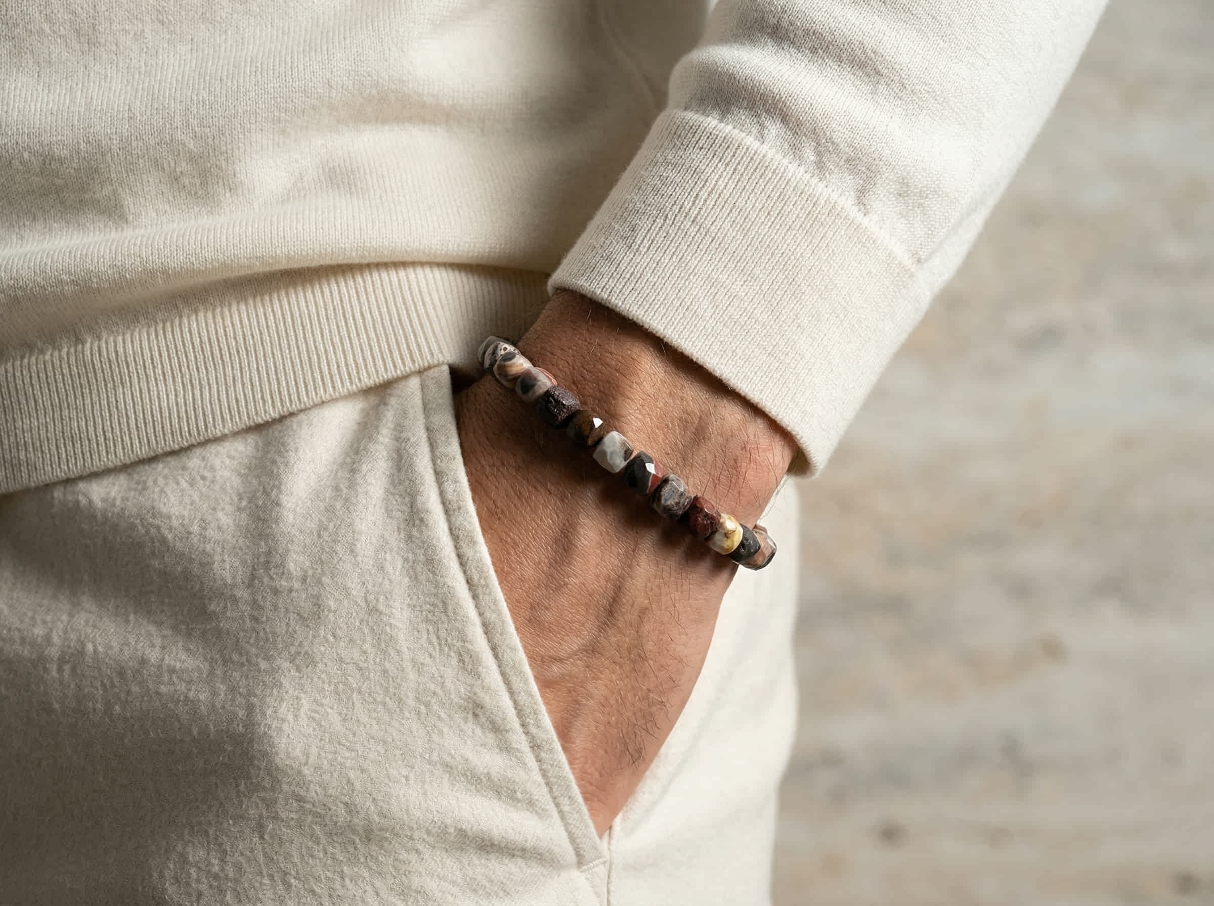 Polsfoto man met witte pullover en armband handgemaakt van gefaceteerde kubus rode laced agaat stenen 6mm